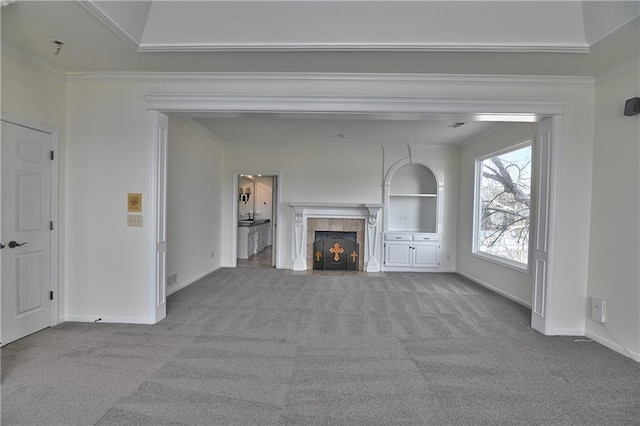 unfurnished living room featuring light colored carpet, ornamental molding, a tiled fireplace, and built in features