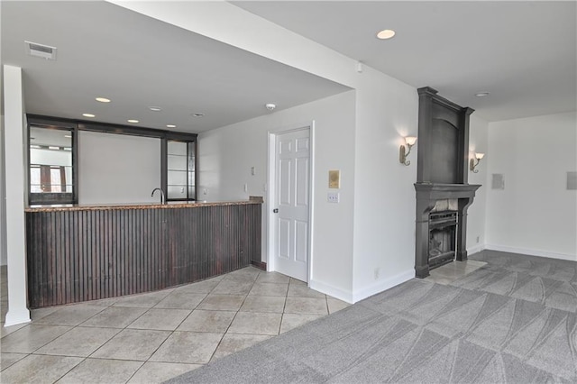 kitchen featuring light tile patterned flooring, a large fireplace, kitchen peninsula, and sink