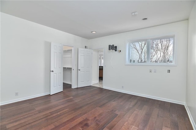 unfurnished bedroom with dark hardwood / wood-style floors, a spacious closet, and a closet