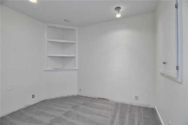 spare room with built in shelves and light colored carpet