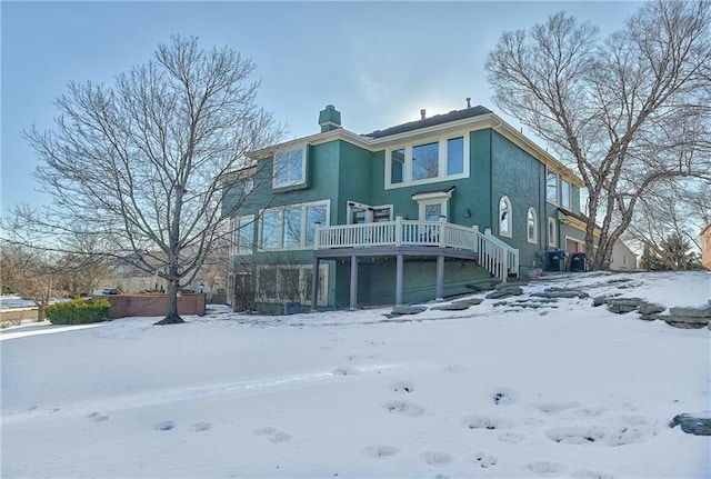 snow covered rear of property featuring a deck