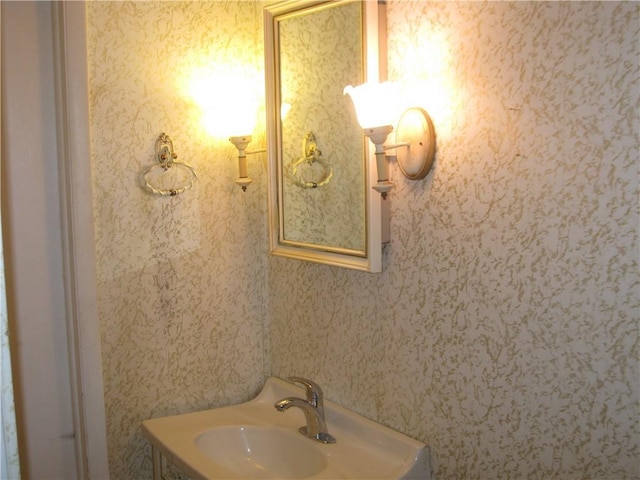 bathroom featuring a sink and wallpapered walls