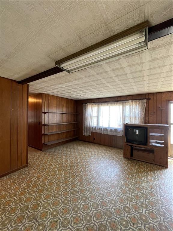 unfurnished living room with tile patterned floors, wood walls, and an ornate ceiling