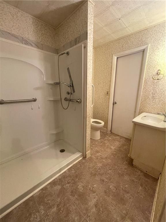 full bathroom featuring vanity, a shower stall, toilet, and wallpapered walls