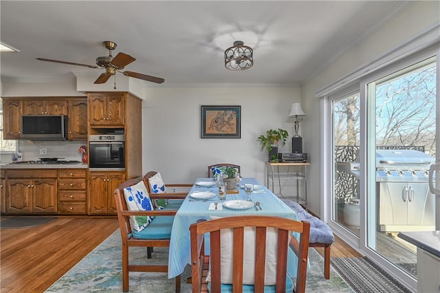 dining space with hardwood / wood-style flooring, ornamental molding, and ceiling fan