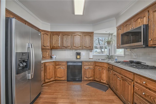 kitchen featuring sink, tasteful backsplash, light hardwood / wood-style flooring, ornamental molding, and stainless steel appliances