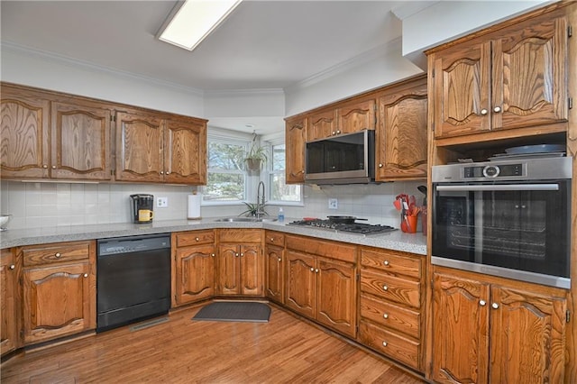 kitchen featuring appliances with stainless steel finishes, sink, decorative backsplash, ornamental molding, and light wood-type flooring