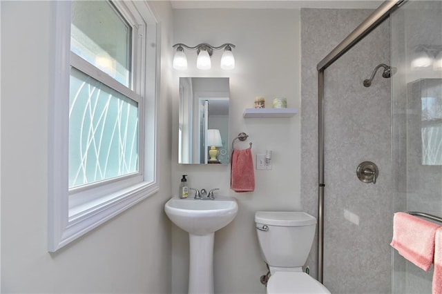 bathroom featuring sink, a shower with door, and toilet