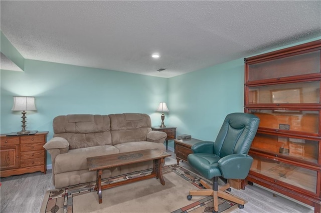 living room featuring light hardwood / wood-style floors and a textured ceiling