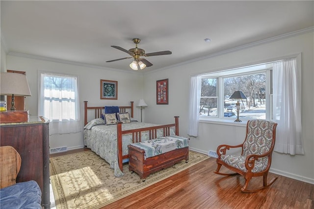 bedroom featuring crown molding, baseboards, multiple windows, and wood finished floors