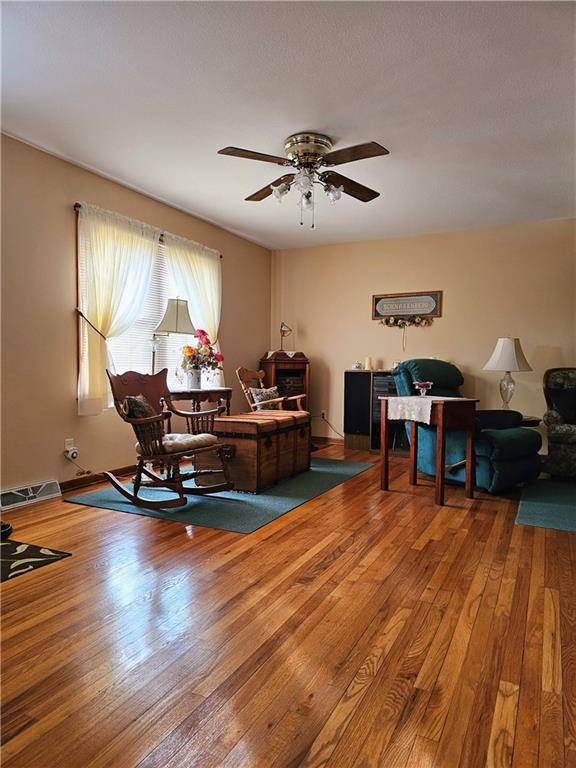 interior space with ceiling fan, hardwood / wood-style floors, and visible vents