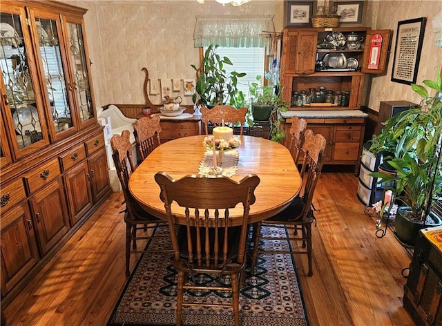 dining space with wood finished floors and wallpapered walls