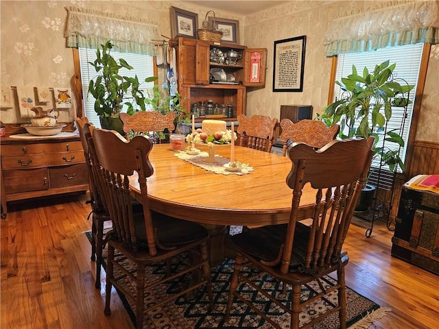 dining space featuring a wainscoted wall, hardwood / wood-style floors, and wallpapered walls