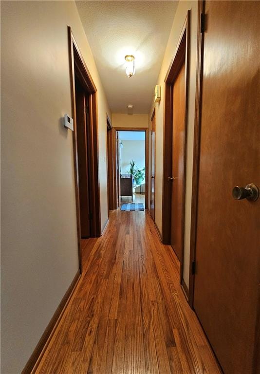 corridor with baseboards and wood finished floors