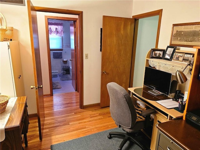 home office featuring light wood finished floors, visible vents, and baseboards