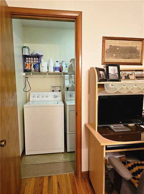 laundry room featuring wood finished floors, washing machine and dryer, and baseboards