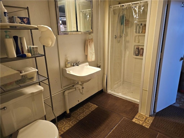 bathroom with tile patterned flooring, a sink, a shower stall, and toilet