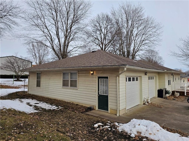 exterior space with a garage and a shingled roof