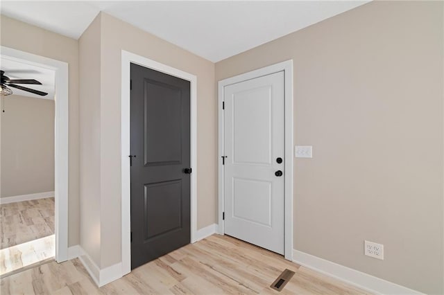 foyer entrance with ceiling fan and light wood-type flooring