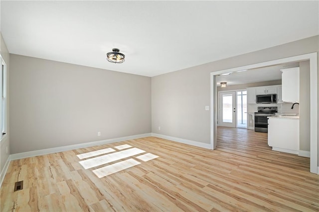 spare room featuring sink and light wood-type flooring