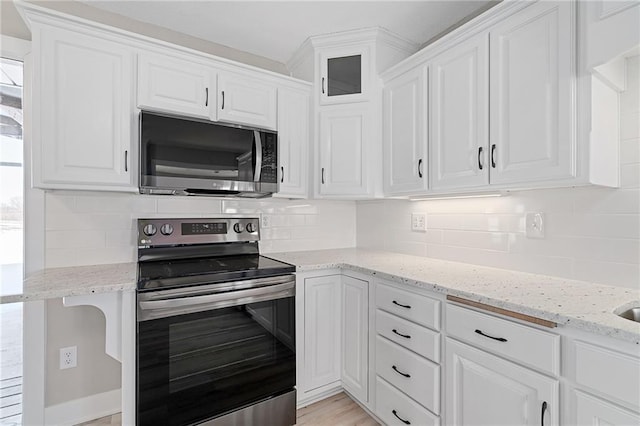 kitchen with white cabinetry, light stone counters, stainless steel appliances, and decorative backsplash