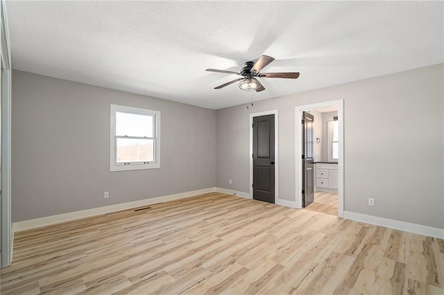 unfurnished bedroom with ceiling fan, light hardwood / wood-style floors, ensuite bath, and a textured ceiling