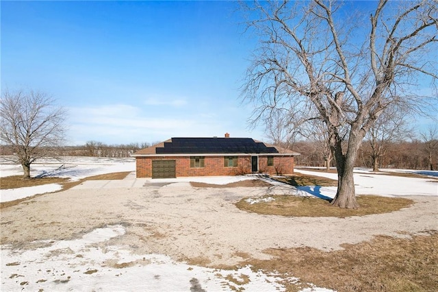 snow covered rear of property featuring solar panels