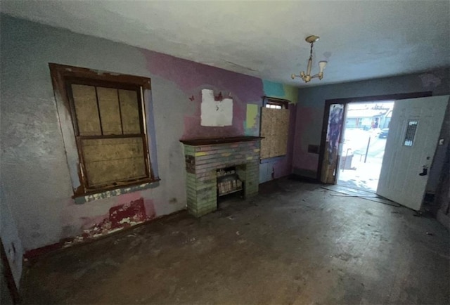 unfurnished living room featuring a brick fireplace and a notable chandelier