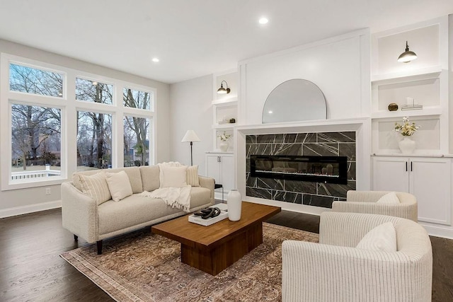 living room featuring dark hardwood / wood-style flooring, a high end fireplace, and built in shelves