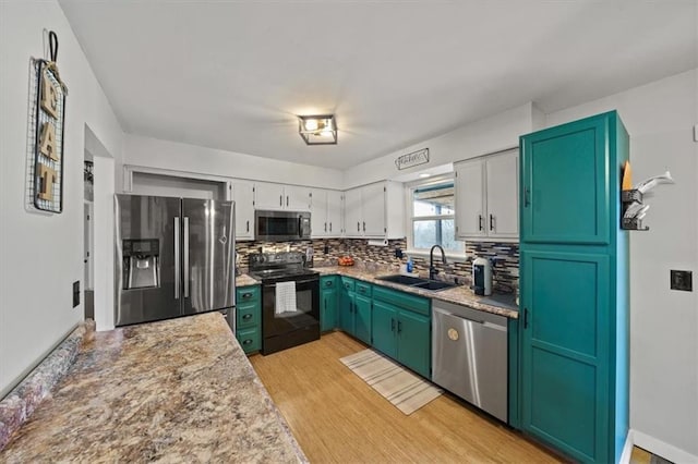 kitchen featuring sink, white cabinetry, appliances with stainless steel finishes, light hardwood / wood-style floors, and decorative backsplash