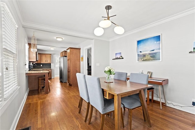 dining space featuring baseboards, ornamental molding, and dark wood-style flooring