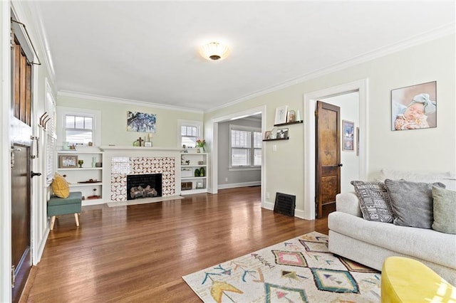 living room featuring baseboards, wood finished floors, a tile fireplace, and ornamental molding