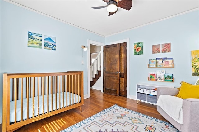 bedroom with a ceiling fan, crown molding, baseboards, and wood finished floors