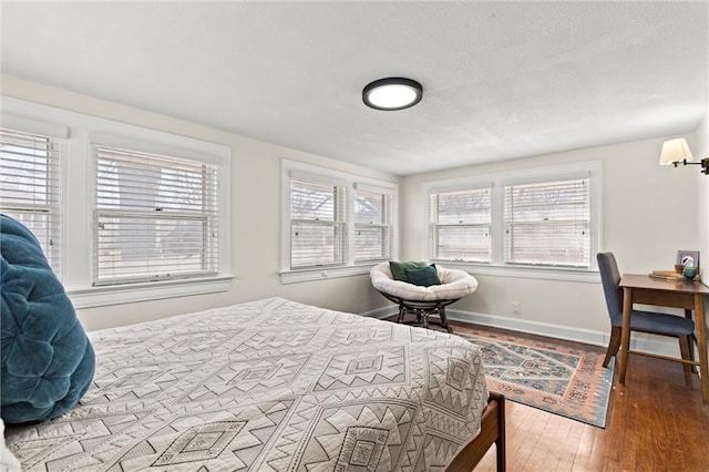 bedroom featuring a textured ceiling, baseboards, and wood-type flooring