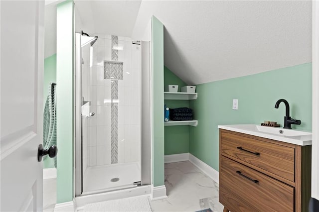 bathroom with lofted ceiling, marble finish floor, a shower stall, baseboards, and vanity