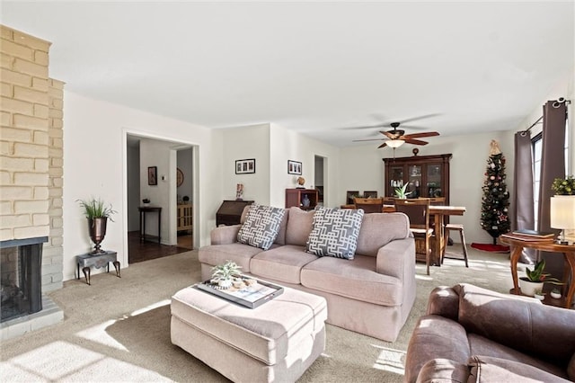 living room featuring a brick fireplace, carpet flooring, and ceiling fan