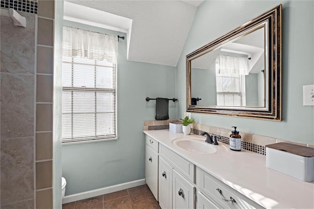 bathroom featuring tile patterned flooring, vanity, lofted ceiling, and plenty of natural light