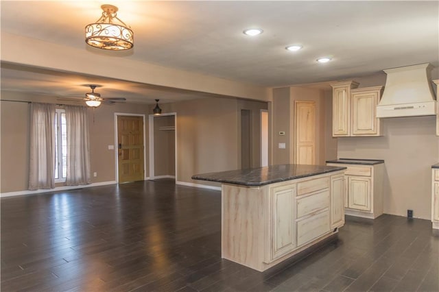 kitchen featuring dark hardwood / wood-style floors, a kitchen island, decorative light fixtures, custom exhaust hood, and cream cabinetry