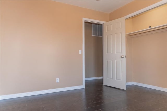 unfurnished bedroom with dark hardwood / wood-style flooring and a closet