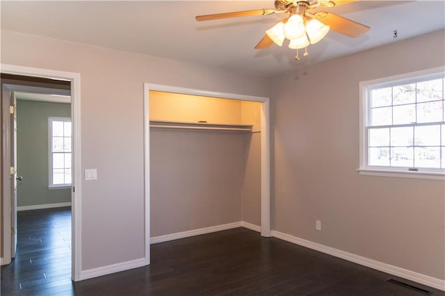 unfurnished bedroom with dark wood-type flooring, ceiling fan, and a closet