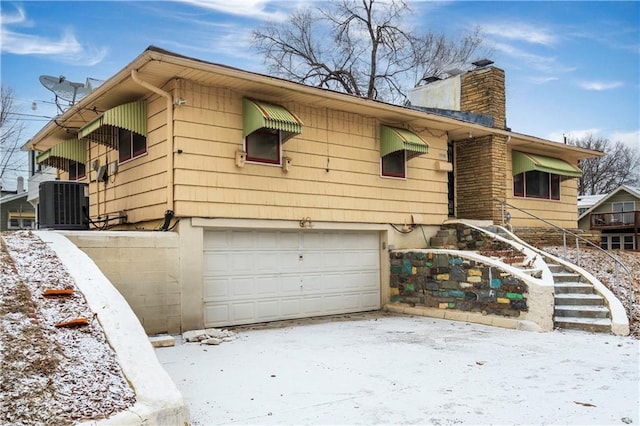 view of front of property featuring an attached garage, a chimney, and central AC unit