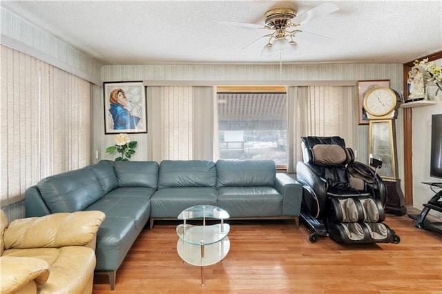 living area with ceiling fan, a textured ceiling, and wood finished floors