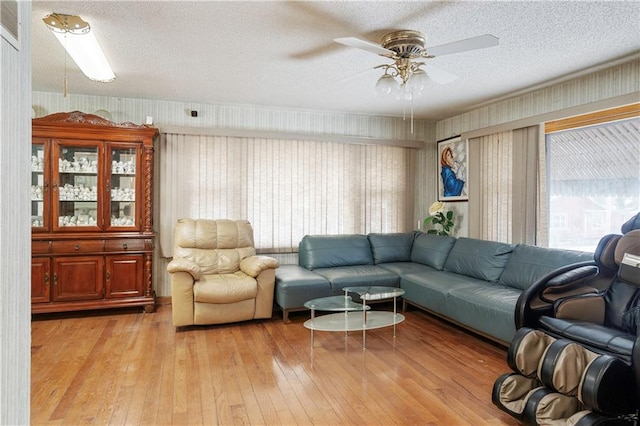 living room with ceiling fan, a textured ceiling, and light wood finished floors