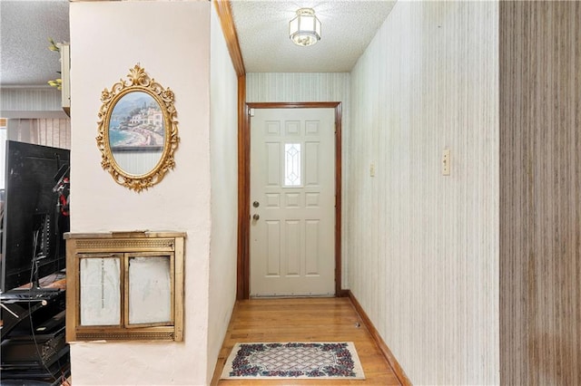 entryway with a textured ceiling, light wood-style flooring, and wallpapered walls