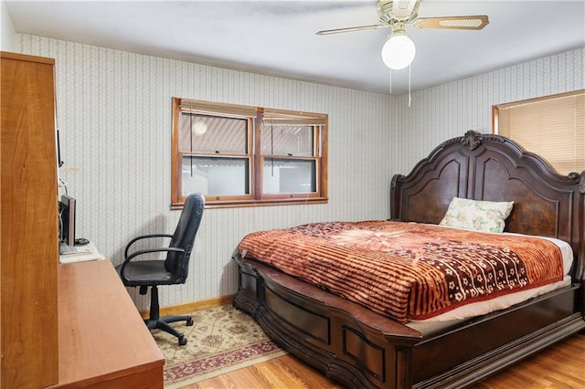 bedroom featuring light wood-type flooring, ceiling fan, baseboards, and wallpapered walls