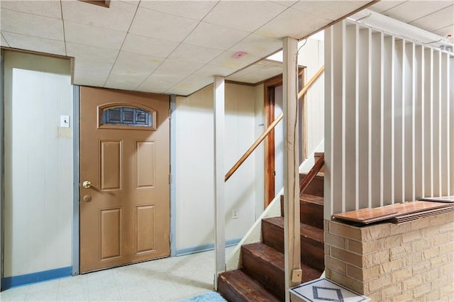 foyer featuring a drop ceiling, stairway, baseboards, and tile patterned floors