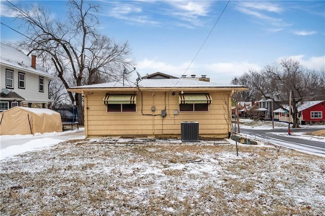 snow covered rear of property with cooling unit and a residential view