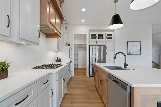 kitchen featuring white cabinetry, sink, stainless steel appliances, and an island with sink