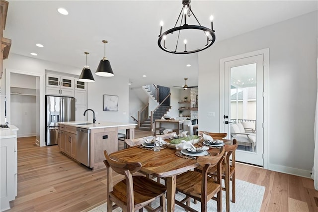 dining space featuring sink, a notable chandelier, and light wood-type flooring