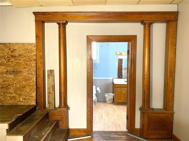 corridor featuring ornate columns and wood-type flooring